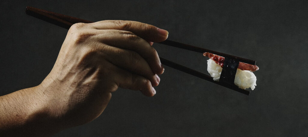 person holding chopsticks with sushi and wondering Is sushi healthy